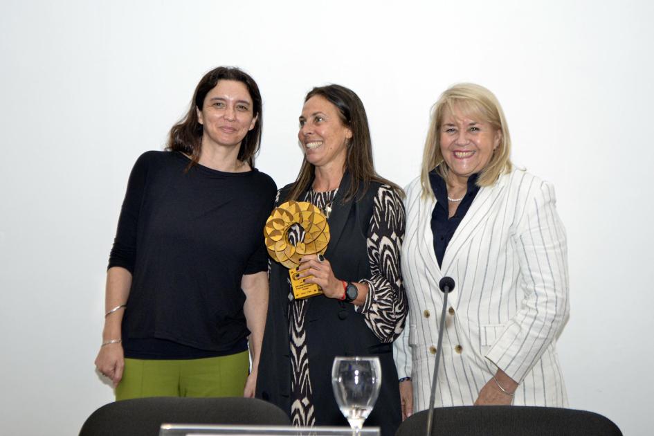 Premio categoría Mipymes con Proyecto de Bioeconomía Circular: Mare Sustentable Una mujer sonríe a otra, sosteniendo el premio; a su lado, Lacuague