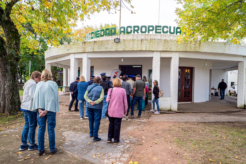 Personas de pie en un jardín, fuera de la Sociedad Agropecuaria de Cerro Largo