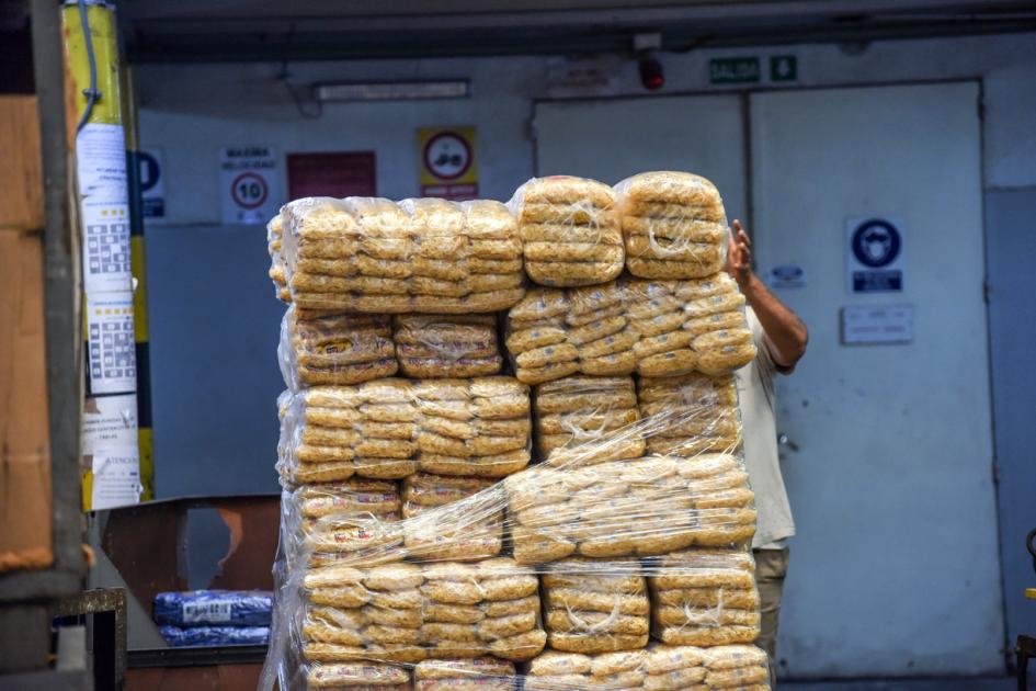 Pila de alimentos envasados; se ve la mano de una persona que los sostiene