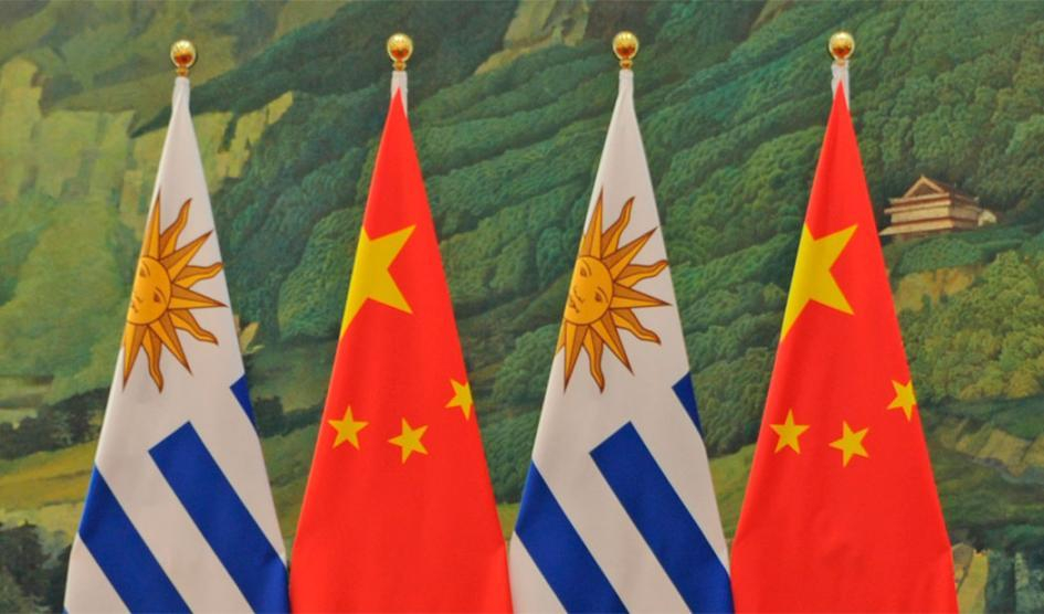 Dos banderas de Uruguay y China; al fondo, paisaje chino
