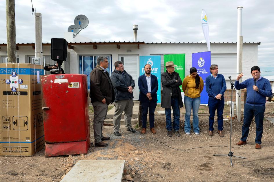 Autoridades reunidas para dar unas palabras; al lado se encuentran las heladeras.