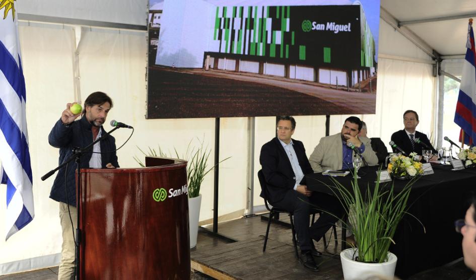 El presidente Luis Lacalle Pou expuso en el evento Presidente Lacalle Pou, detrás de un atril, sostiene un limón; a su lado, mesa de autoridaes