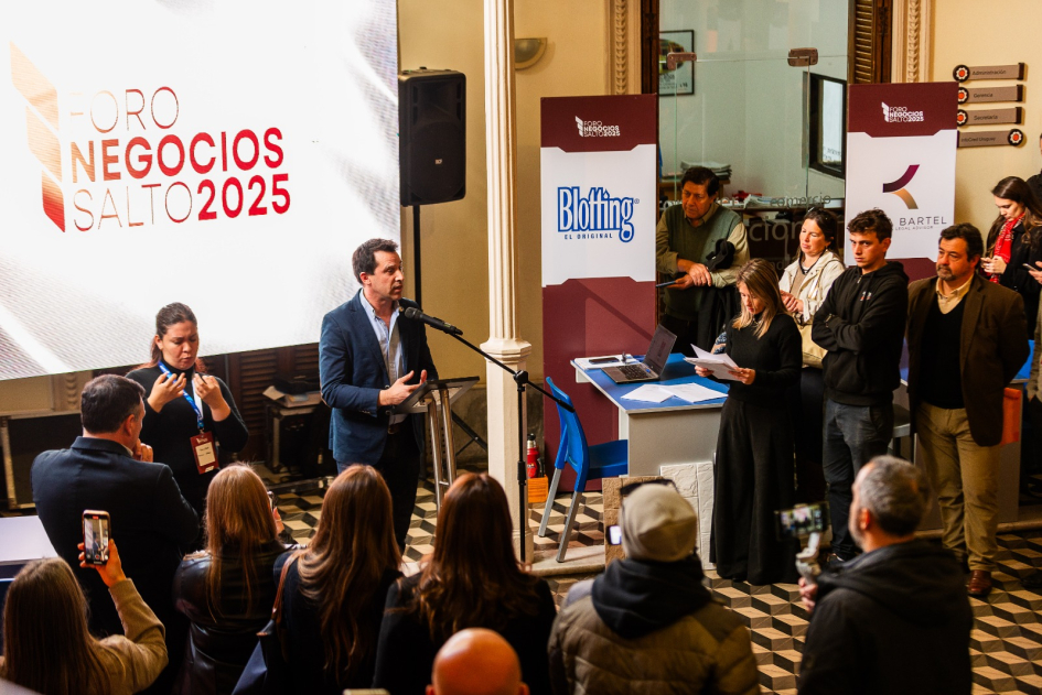 Apertura del Foro Salto 2025 Personas de pie; un hombre habla de pie; detrás, una pantalla