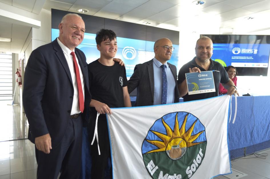 Verri, un adolescente, Albaladejo y un hombre sostienen una bandera que dice El Mate Solar