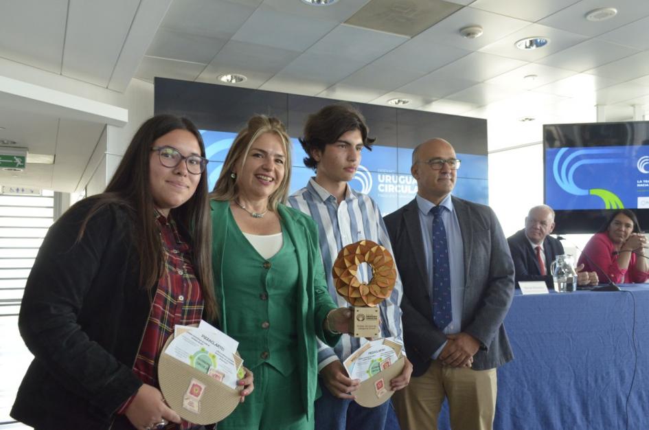 Albaladejo junto a dos adolescentes (un chico y una chica; sostienen carpetas) y una mujer