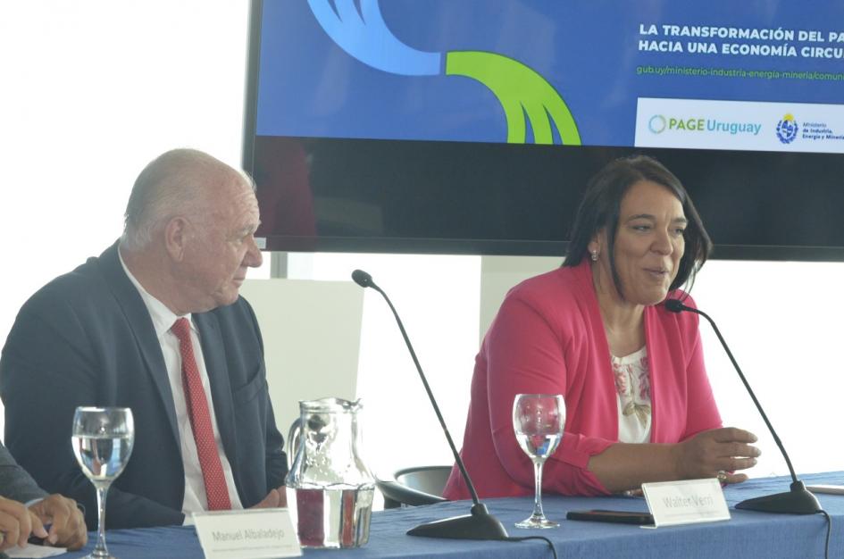 Carmen Sánchez y Walter Verri Sánchez habla junto a Verri; arriba, pantalla con el logo
