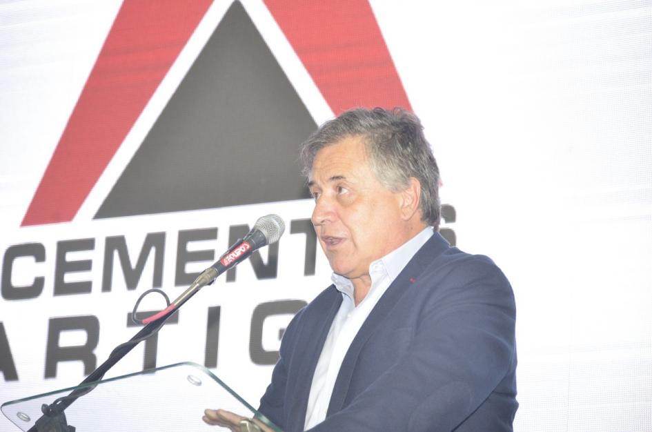 Ministro Omar Paganini Paganini habla con un micrófono; detrás, logo de Cementos Artigas