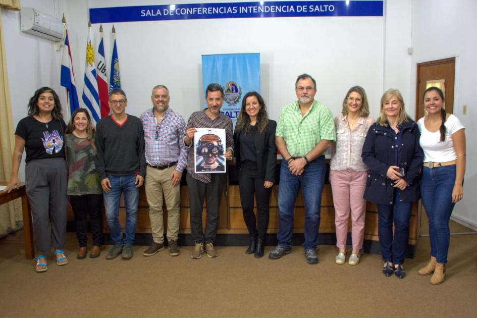 Ceremonia de lanzamiento del concurso Personas posan, de pie; detrás hay una bandera uruguaya