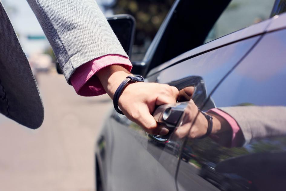 Mano de persona abre un auto de color oscuro