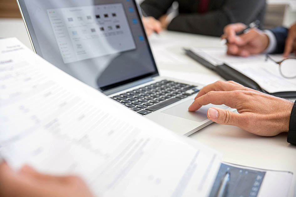Las postulaciones para la consultoría se reciben hasta el 30 de julio Manos de personas en un escritorio en que hay una computadora y documentos