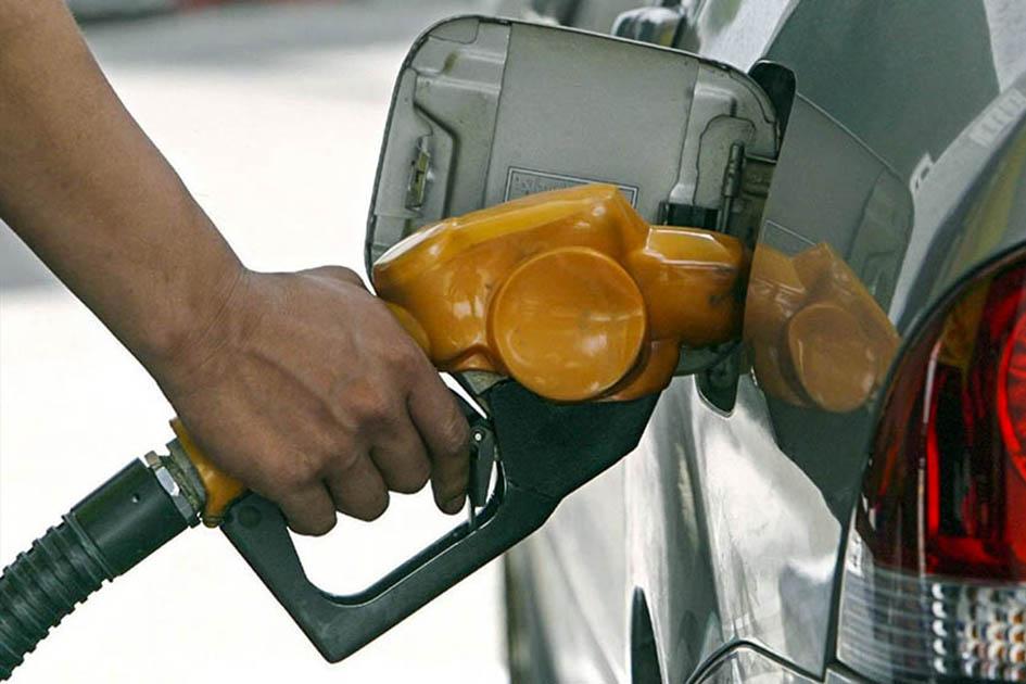 Los combustibles no aumentarán de precio en julio Mano con un surtidor de combustible, cargando un auto de color gris