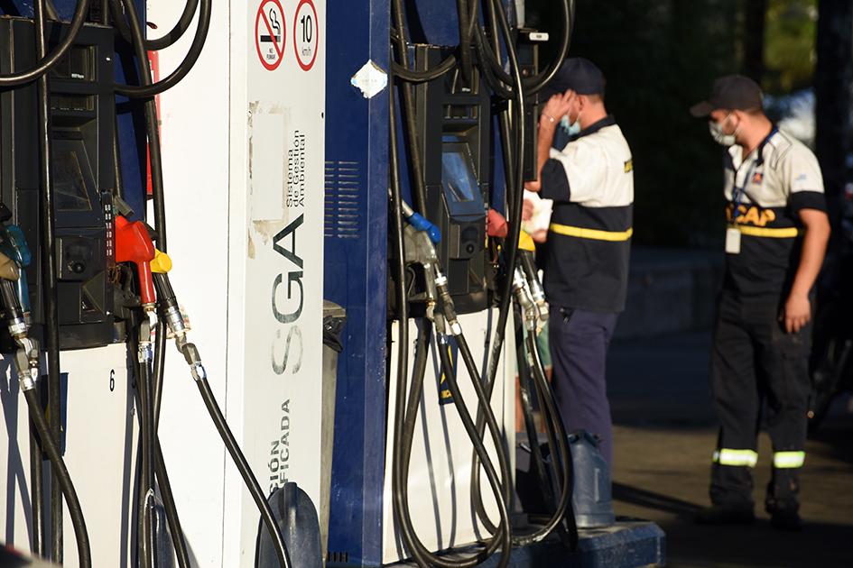Los combustibles no aumentarán su precio en agosto Dos trabajadores se ven junto a surtidores de combustibles