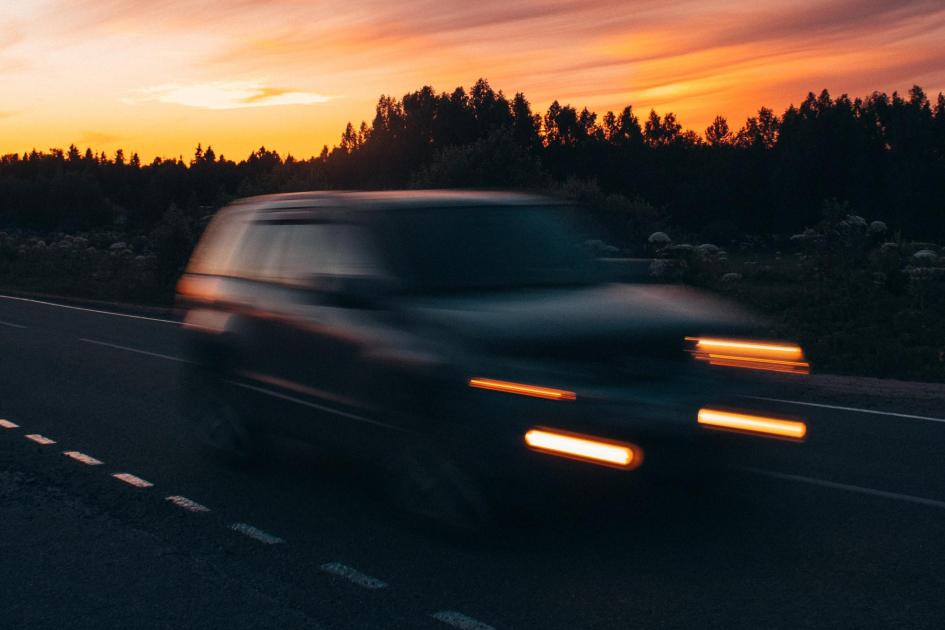 Auto, con luces prendidas, en la hora del atardecer