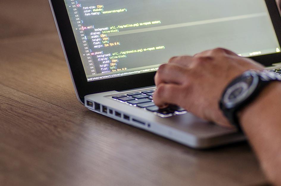 Se ve la mano de un hombre escribiendo en una laptop