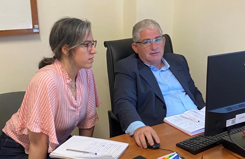 El experto dialogó con los funcionarios de ARNR Funcionaria de la ARNR y experto del OIEA sentados frente a un escritorio mientras trabajan