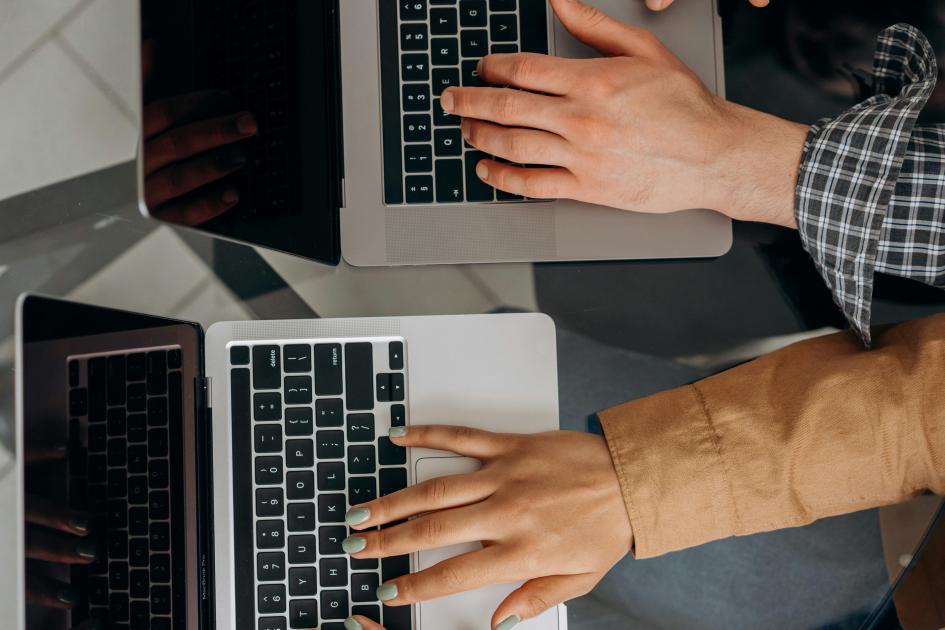 Dos pasantes colaborarán con el desarrollo de las mipymes de Río Negro, gracias al apoyo del MIEM Manos de un joven y de una joven que escriben en laptops
