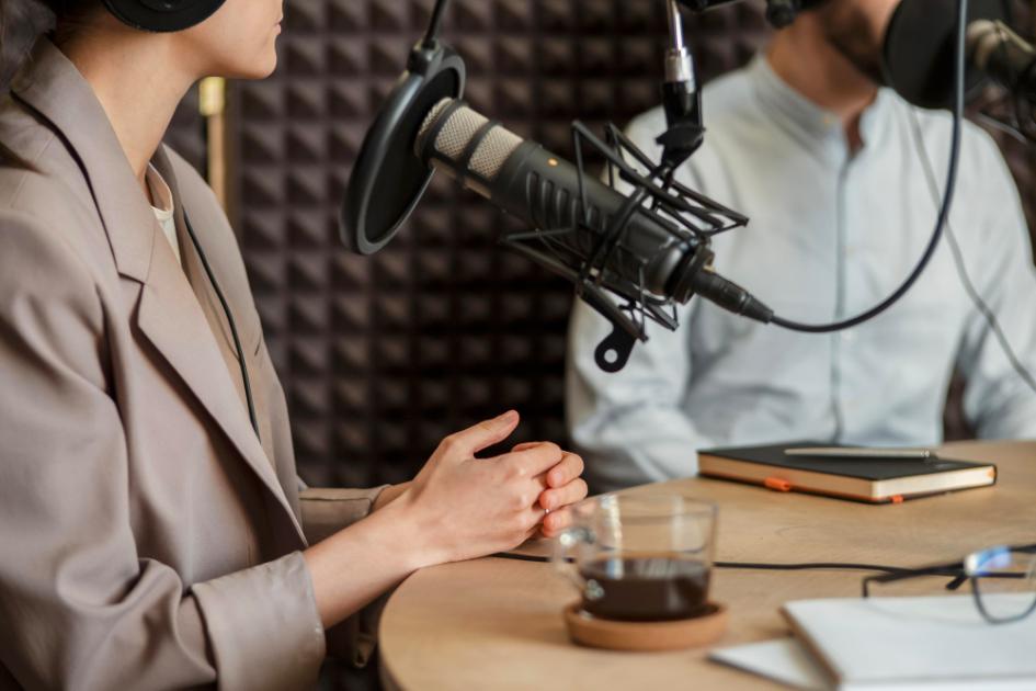 dos personas en estudio de grabación realizando un programa radial frente a micrófono