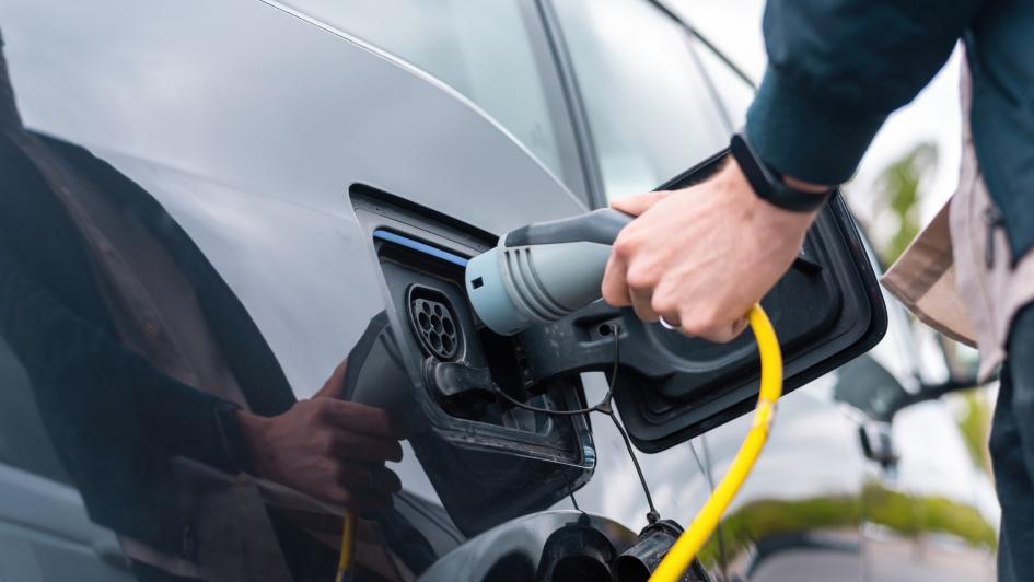Movilidad eléctrica Se muestra una mano conectando cargador al vehículo eléctrico