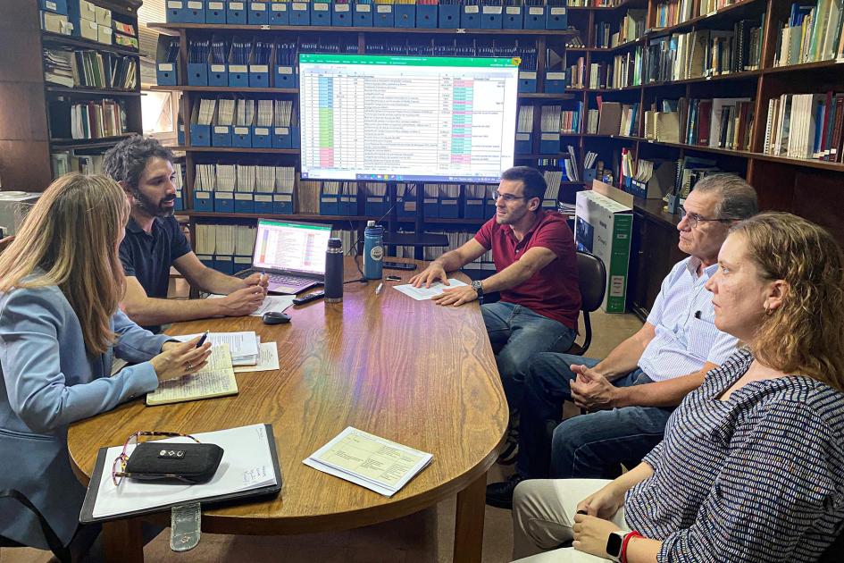 Reunión en la Facultad de Ingeniería Grupo de personas alrededor de una mesa; al fondo, una pantalla