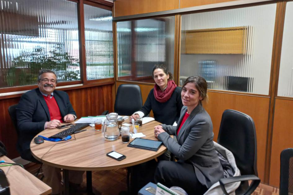 Dos mujeres y un hombre están reunidos alrededor de una mesa, en una oficina