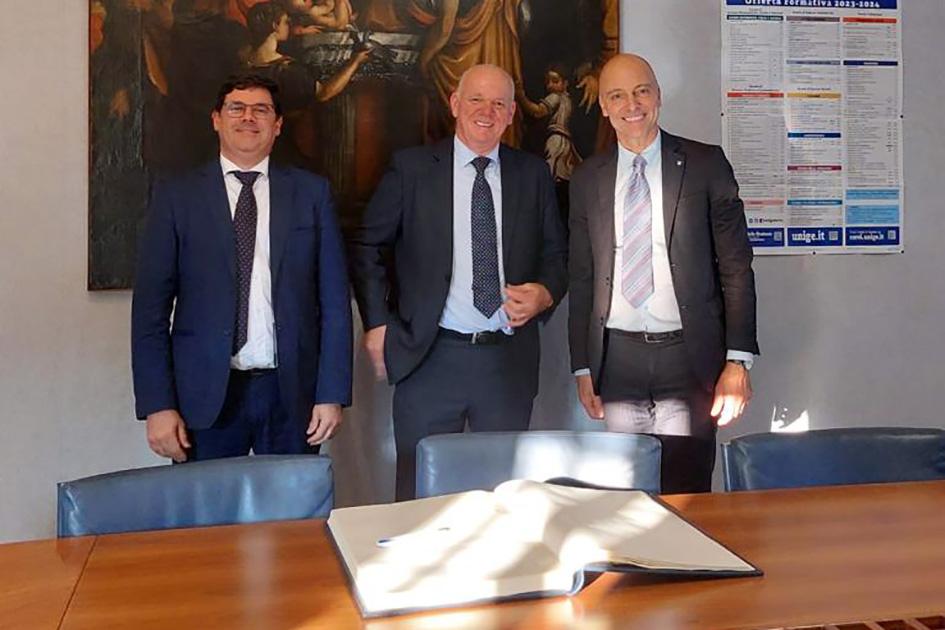 Reunión en la Universidad de Génova Verri, Cantero y otro hombre posan, detrás de una mesa, en una oficina; detrás hay un cuadro