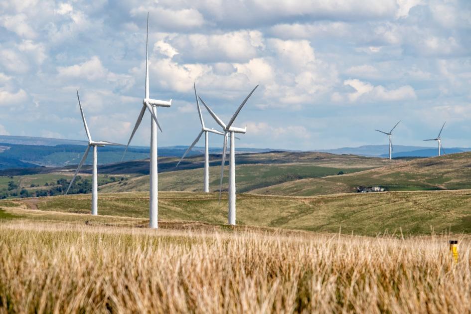 Molinos de viento en una pradera, bajo un cielo soleado pero cargado de nubes