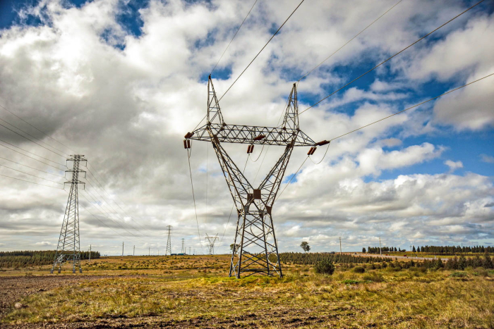 La ministra Fernanda Cardona habló sobre interconexión energética ante un auditorio regional Torre eléctrica en el campo, bajo un cielo con nubes