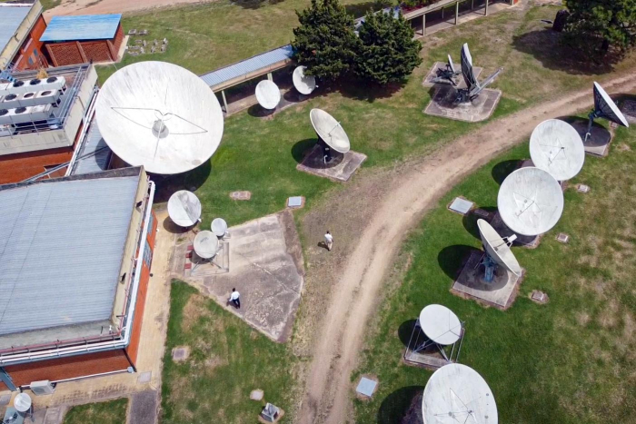 Estación Terrena de Antel en Manga-Polo de Tecnologías Espaciales Antenas parabólicas, edificaciones y árboles, sobre el pasto