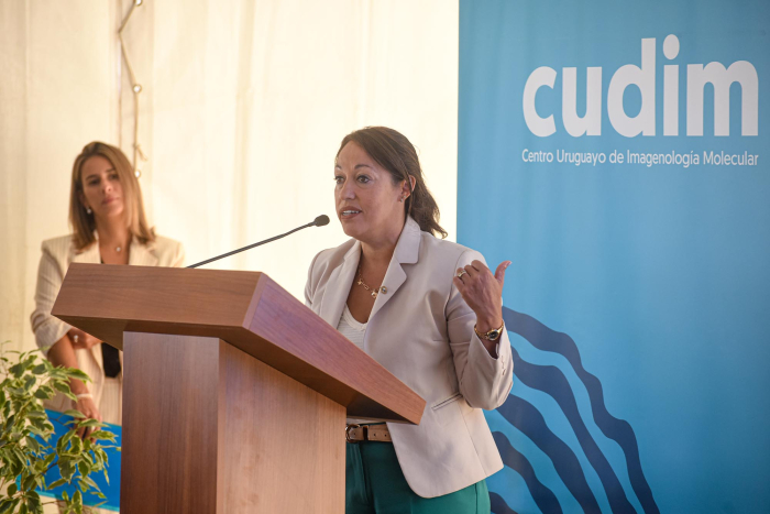 Ministra Cradona en expone en atril, detrás un banner de CUDIM 