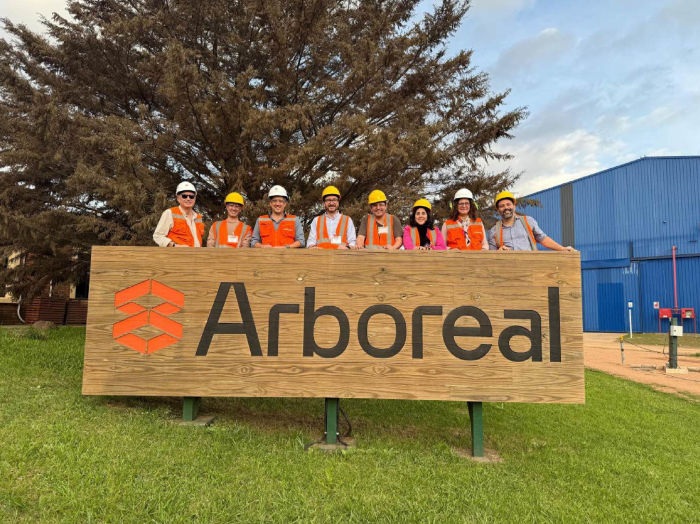 Personas visten chalecos y cascos detrás de un cartel de Arboreal