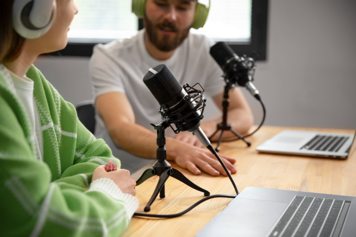 La convocatoria estará abierta hasta el 24 de noviembre. Mujer y hobmre conversan frente a sus micrófonos en estudio de radiodifusión (imagen de Freepik)