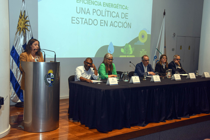 Ministra Cardo hablando desde un atril, al lado de ella mesa de oradores con autoridades