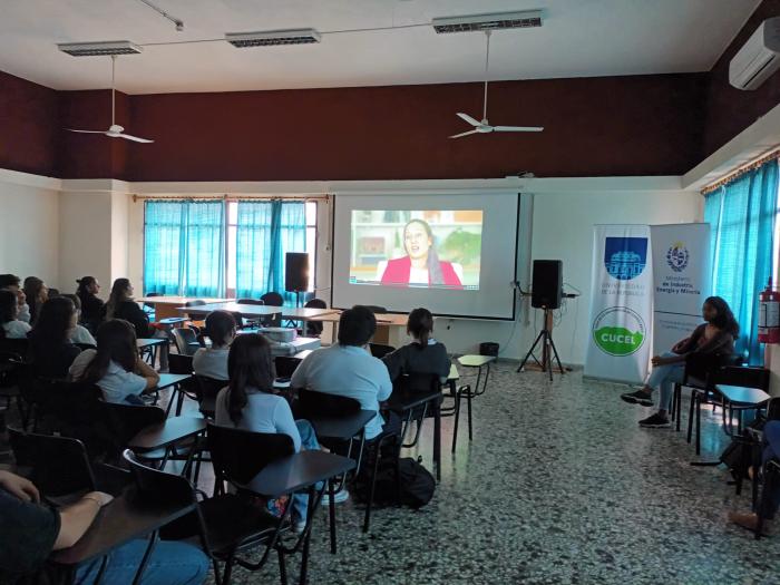 Grupo de personas sentadas en una sala, viendo una pantalla