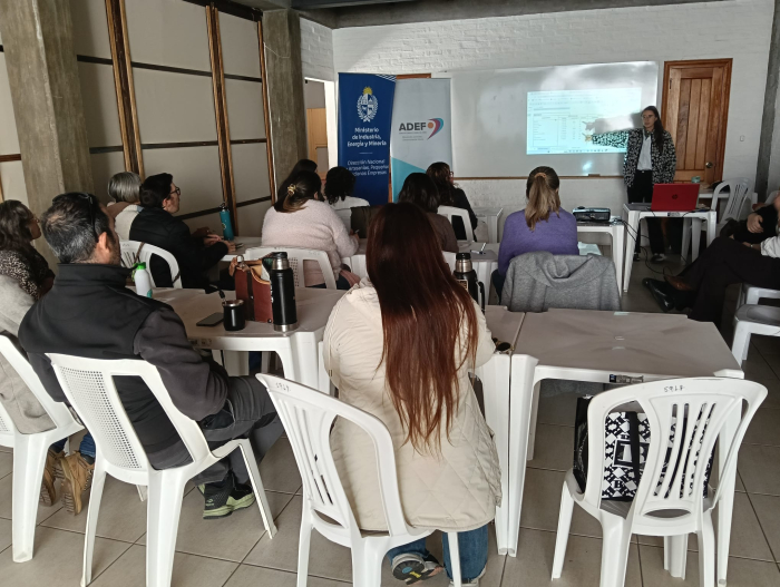Taller de innovación de productos con integrantes de la cocina comunitaria de Florida Personas sentadas en sillas; al fondo, una mujer señala un pizarrón, de pie