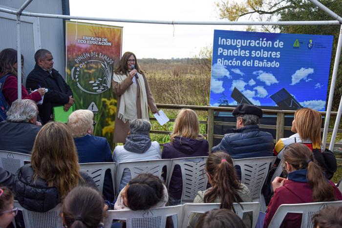 La ministra Elisa Facio habló en la inauguración de paneles solares en Rincón del Bañado Ministra Facio habla frente al público de espaldas; detrás, pantalla. Están al aire libre.