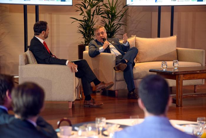 Ministro Omar Paganini Paganini habla desde un sillón doble; a su lado, en un sillón simple, hay otro hombre