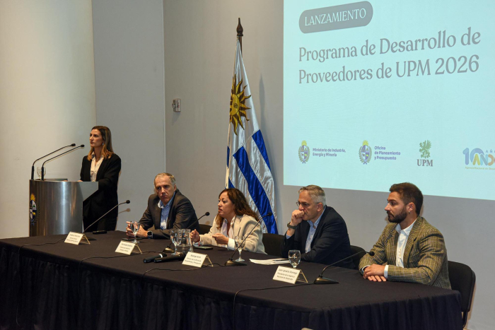 Lanzamiento del Programa de Desarrollo de Proveedores Nacionales de UPM 2026 Cuatro personas en mesa de autoridades; al lado, maestra de ceremonias; detrás, pantalla