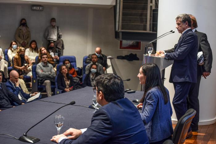 Mesa de autoridades y maestros de ceremonia vistos de atrás; a lo lejos, el público