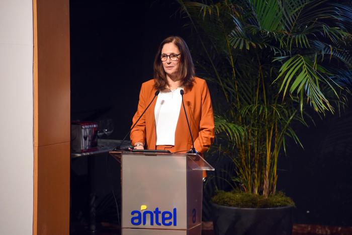 Facio habla desde un atril con el logo de Antel; detrás, plantas
