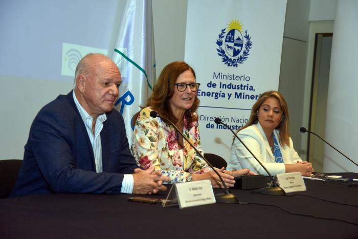 Facio habla; a su lado, Pecoy y Verri; detrás, banner del MIEM