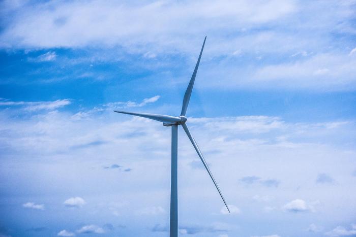 Aerogenerador bajo un cielo con algunas nubes