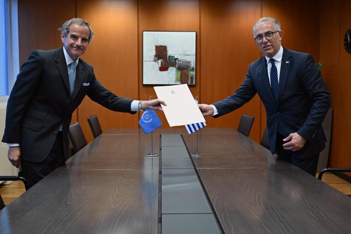 Director general del OIEA y embajador de Uruguay en Austria se dan la mano a los lados de una mesa
