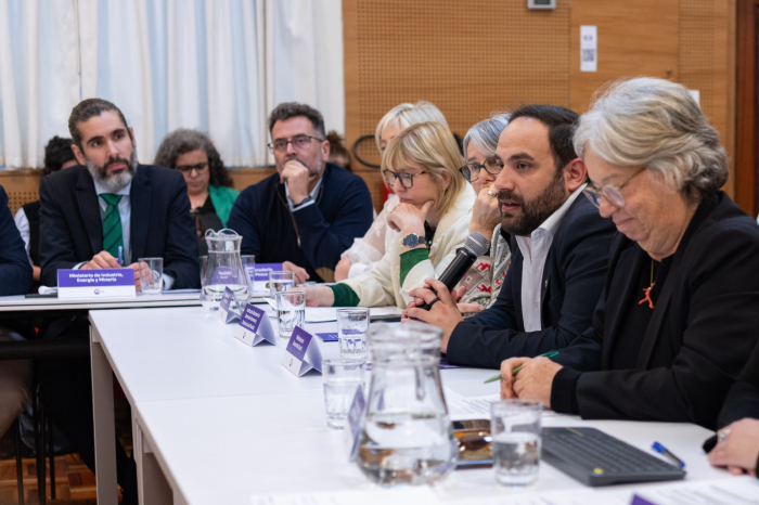 Personas sentadas en mesa en forma de "u"; habla el ministro Civila