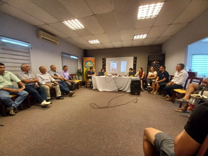 Personas reunidas en un salón, en ronda; al fondo, mesa