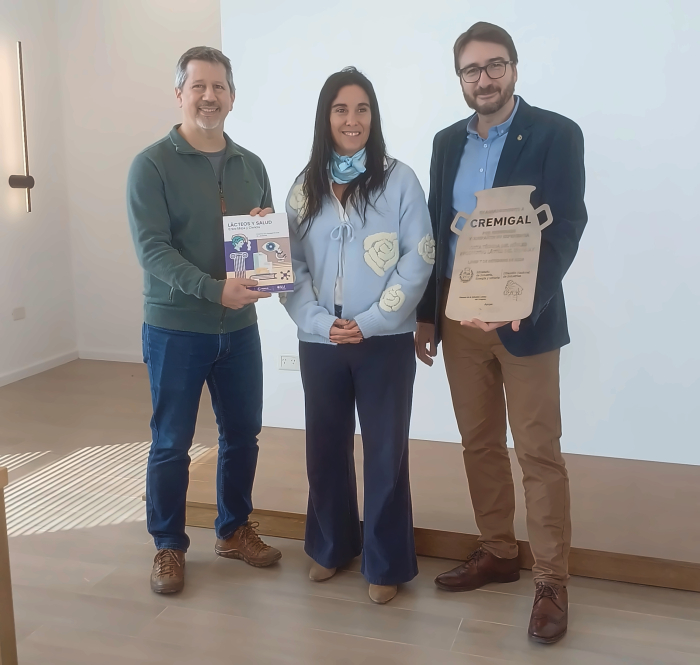 Director Míguez, de pie, con un hombre y una mujer; sostienen materiales de Cremigal