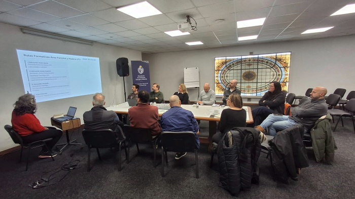 Reunión del Núcleo Productivo Forestal Maderero y UTU Personas sentadas en círculo alrededor de mesa; a la izquierda, una pantalla