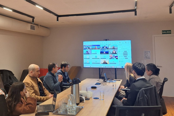 Taller sobre infraestructura de carga para vehículos eléctricos Participantes en una mesa y con conexión de forma virtual