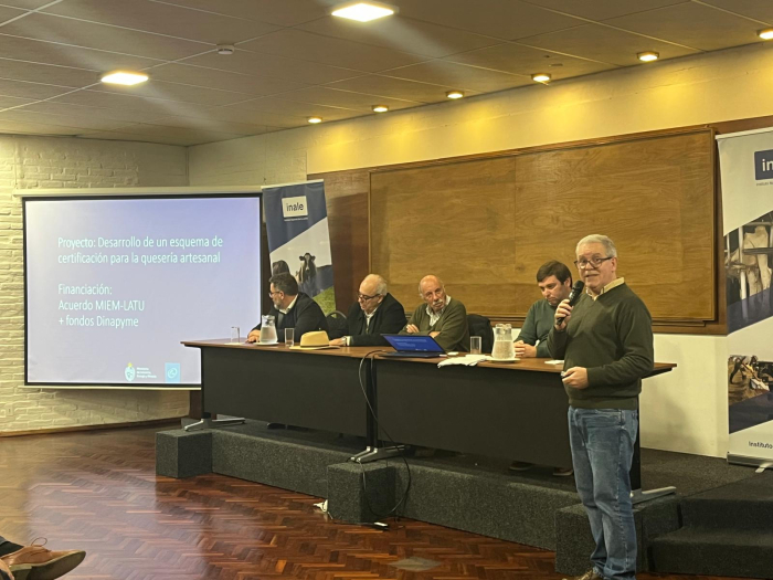 Presentación de la certificación, con la participación de Dinapyme Personas sentadas en una mesa; a un lado, persona de pie; del otro, pantalla