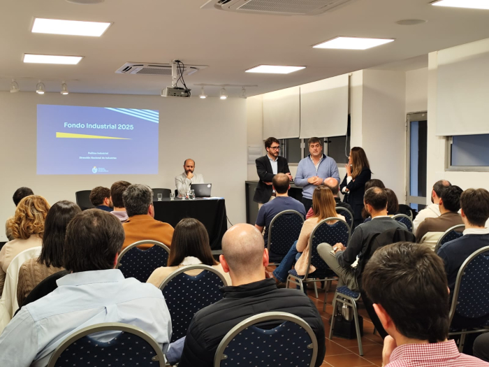 Director de Industrias habla en el taller; se lo ve al fondo; más cerca, público