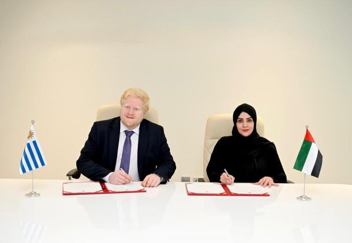 Firma del acuerdo Nieves y una representante de Emiratos Árabes Unidos firman el acuerdo; sobre la mesa, banderas